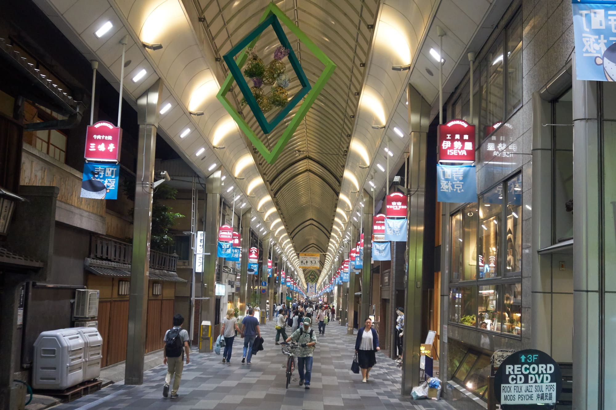 The covered Teramachi shopping arcade, with its arched glass roof, hanging banners and a wooden machiya storefront on the left.
